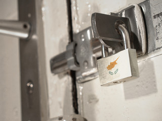 A bolted door secured by a padlock with the national flag of Cyprus on it.(series)