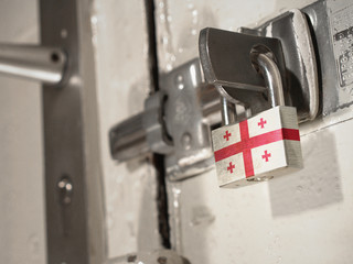 A bolted door secured by a padlock with the national flag of Georgia on it.(series)