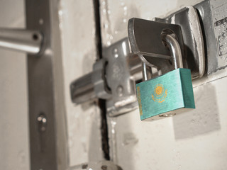 A bolted door secured by a padlock with the national flag of Kazakhstan on it.(series)