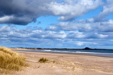 Deserted Beach with huge cloudy  blue sky and sand dunes in the foreground, Bamburgh, Northumberland, Uk