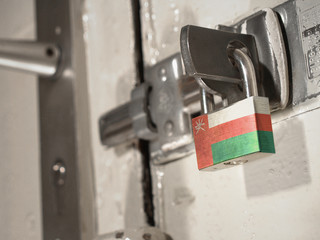 A bolted door secured by a padlock with the national flag of Oman on it.(series)