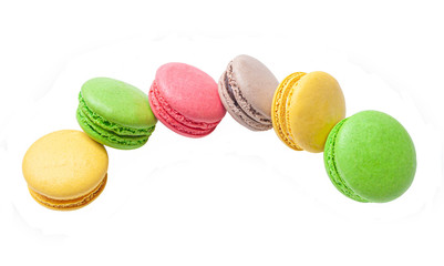 six macaroons of yellow , green, pink and brown colors lie in a semicircle on a white isolated background