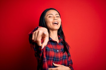 Young beautiful chinese woman wearing casual shirt over isolated red background laughing at you, pointing finger to the camera with hand over body, shame expression