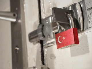 A bolted door secured by a padlock with the national flag of Turkey on it.(series)