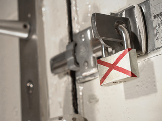 A bolted door secured by a padlock with the national flag of Alabama on it.(series)