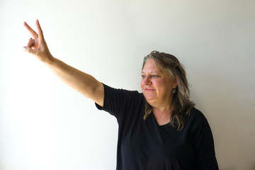 Old woman doing number two gesture on white background. Gesturing number 2. Peace or victory symbol. Number two / letter V in sign language. Being second concept. Hand counting two. Space for ad text.