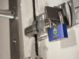 A bolted door secured by a padlock with the national flag of Kansas on it.(series)