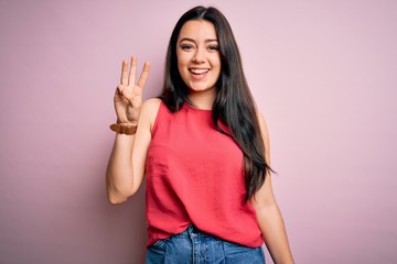 Young brunette woman wearing casual summer shirt over pink isolated background showing and pointing up with fingers number three while smiling confident and happy.