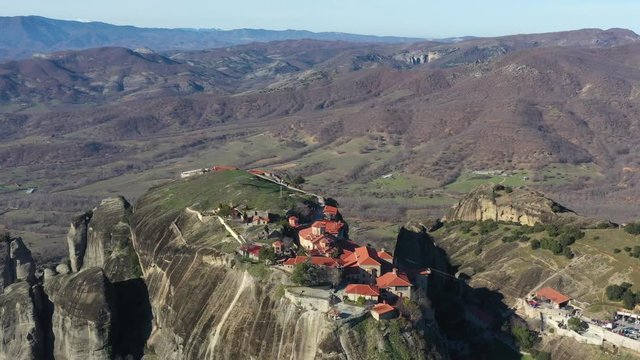 Kalambaka, Greece, Aerial view of monastery Varlaam and breathtaking pictures of valley and landmark canyon of Meteora at sunrise, Cradle on a ropeway, a lot of tourists, red roofs of monastery