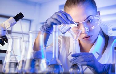 Laboratory interior. Science research concept. Young scientist during experiment and using microscope in modern laboratory.
