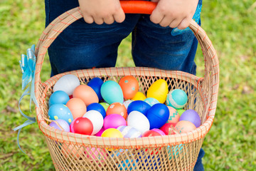 Close up Little boy holding basket full of colorful easter eggs