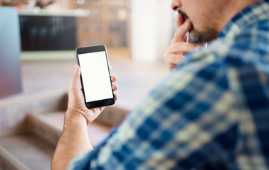 Mockup of a man in thoughts that holding a smartphone in his hand. Close up shot. Clipping path included.