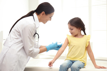 Doctor vaccinating little child in modern clinic