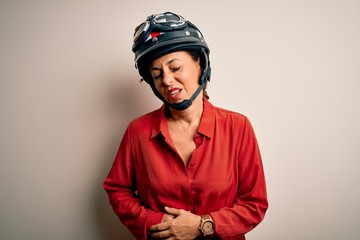 Middle age motorcyclist woman wearing motorcycle helmet over isolated white background with hand on stomach because indigestion, painful illness feeling unwell. Ache concept.