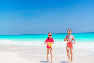 Little happy funny girls have a lot of fun at tropical beach playing together.