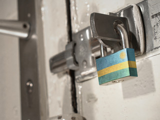 A bolted door secured by a padlock with the national flag of Rwanda on it.(series)