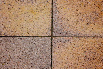 Texture of an old sidewalk in the Venetian style. Part of the sidewalk grainy square tiles in pink and yellow shades in the Renaissance style close- up from above.