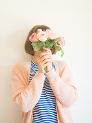 Young woman holding bouquet of pink flowers covering her face. Bright faceless female portrait. Womens, mothers day concept