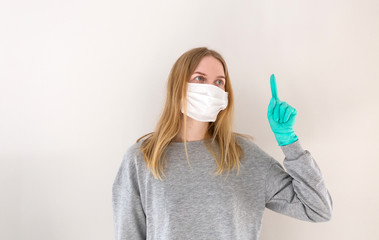Blonde woman investigating in medical mask pointing up a great idea. The concept of the epidemic of the coronavirus and anti-smog. Corona virus 2019-ncov covid-19. People and body language.