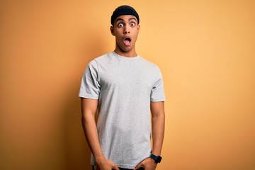 Handsome african american sportsman doing sport wearing sportswear over yellow background In shock face, looking skeptical and sarcastic, surprised with open mouth