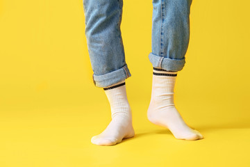 Male legs in socks and jeans on color background