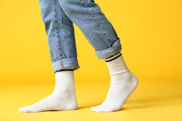 Male legs in socks and jeans on color background