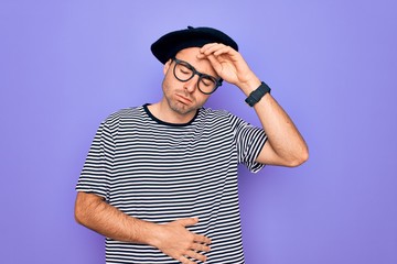 Handsome man with blue eyes wearing striped t-shirt and french beret over purple background Touching forehead for illness and fever, flu and cold, virus sick