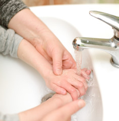 child washes hands in bathroom