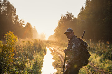 Silhouetted of a hunter with shotgun at beautiful sunset - 332269988