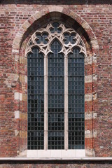 Pointed ogive window with gothic cinquefoil tracery at the brick facade of Engelse Kerk church in Middelburg, the Netherlands