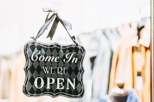 Panneau suspendu sur une devanture Come In We're Open