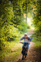 Joyful boy on a bicycle with his parents in the park