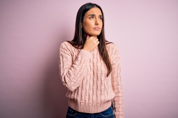 Fototapeta premium Young beautiful brunette woman wearing casual sweater over isolated pink background Touching painful neck, sore throat for flu, clod and infection