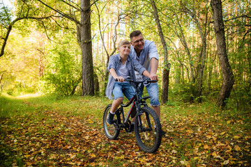 Fototapeta na wymiar young father teaching his smiling son how to ride a bike