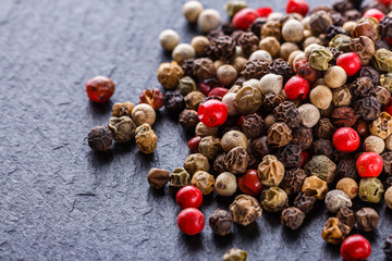 mix of peppercorns on a dark stone background