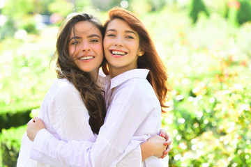 Fototapeta premium Happy women talking and laughing in a park with a green spring background.