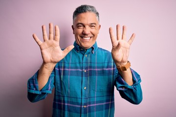 Naklejka premium Middle age handsome grey-haired man wearing casual shirt over isolated pink background showing and pointing up with fingers number nine while smiling confident and happy.