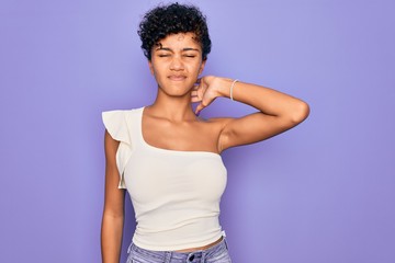 Fototapeta na wymiar Young beautiful african american afro woman wearing casual t-shirt over purple background Suffering of neck ache injury, touching neck with hand, muscular pain