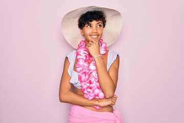 Young beautiful african american tourist woman wearing bikini and hawaiian lei flowers with hand on...