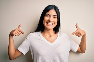 Young beautiful hispanic woman wearing casual white t-shirt over isolated background looking...