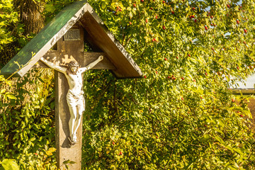 Wayside cross with in Bavaria next to a tree in autumn