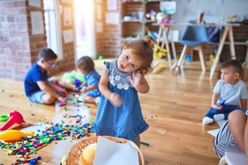 Adorable group of toddlers playing around lots of toys at kindergarten