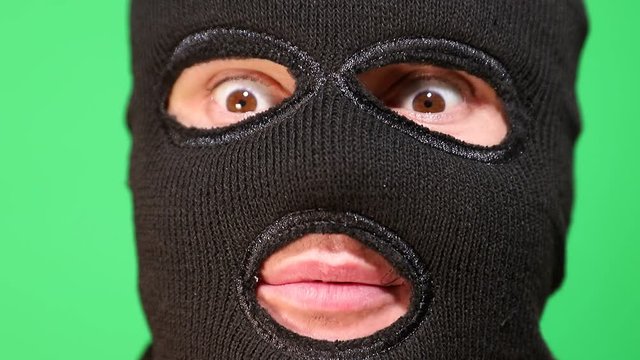 Scary thief or robber in mask looking at camera. Portrait of man in balaclava