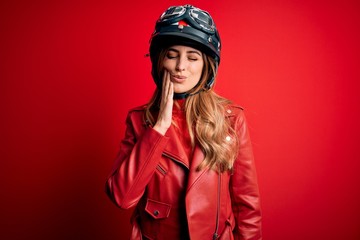 Young beautiful brunette motrocyclist woman wearing moto helmet over red background touching mouth with hand with painful expression because of toothache or dental illness on teeth. Dentist