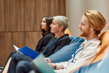 The power behind teamwork. Multiethnic work group listening to speaker during informal briefing or meeting, discussing business ideas and sharing thoughts