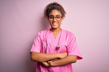 African american nurse girl wearing medical uniform and stethoscope over pink background happy face...