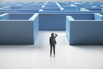 Businesswoman standing at entrance to a blue maze.