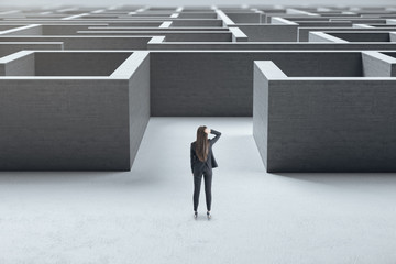 Businesswoman standing at entrance to a concrete labyrinth.