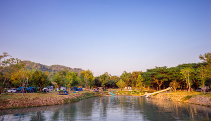 Fototapeta premium Camping and tent in nature park with mountain and blue sky near the river