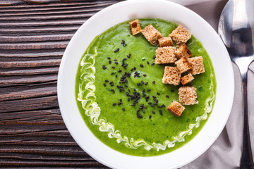 broccoli spinach cream soup on rustic wooden background